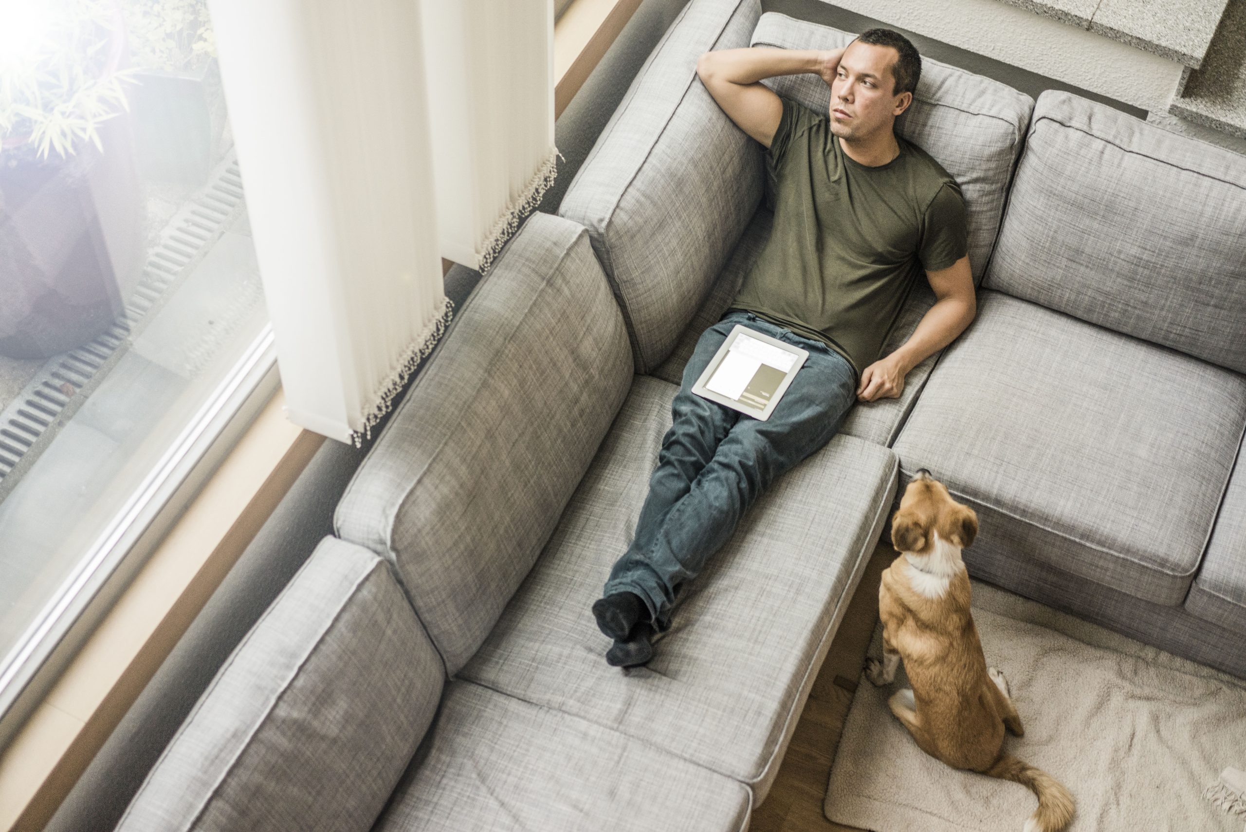 man-at-home-with-tablet-on-the-couch-with-dog-besi-2023-11-27-05-03-11-utc-masolat-scaled.jpg